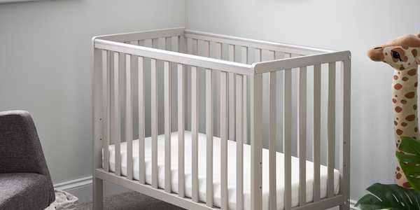 A nursery with a grey cot and a basket near it.
